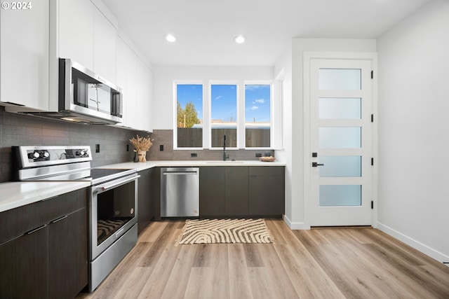 kitchen featuring dark brown cabinets, light hardwood / wood-style flooring, appliances with stainless steel finishes, sink, and white cabinetry