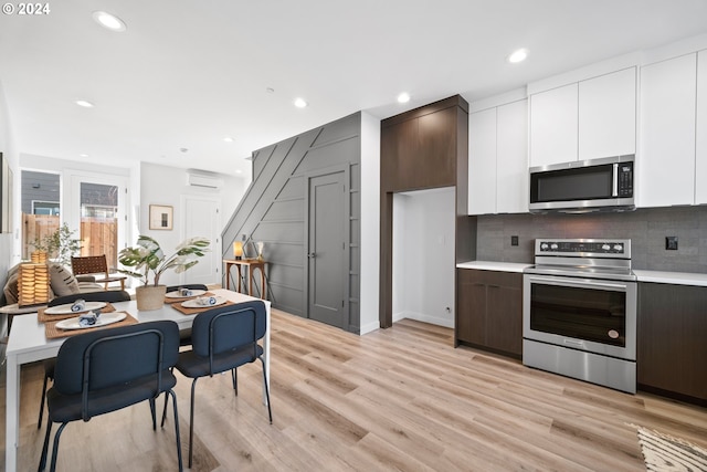 kitchen featuring modern cabinets, white cabinetry, stainless steel appliances, light wood-style floors, and light countertops