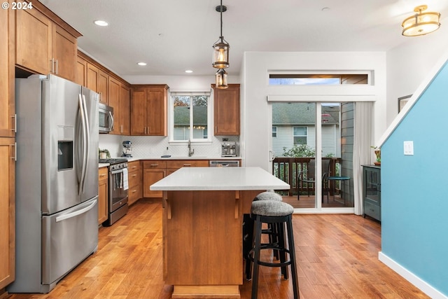 kitchen featuring appliances with stainless steel finishes, a center island, light hardwood / wood-style flooring, and pendant lighting