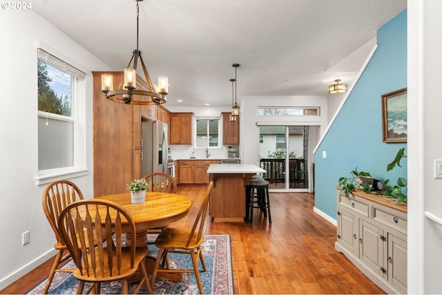 dining room with a notable chandelier, plenty of natural light, light wood-type flooring, and sink