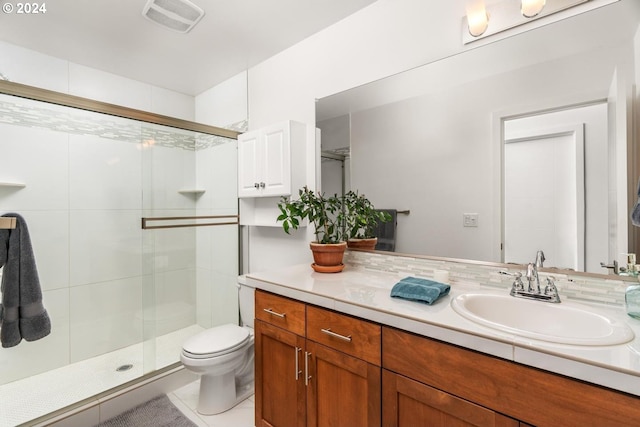 bathroom with tile patterned flooring, vanity, toilet, and a shower with shower door