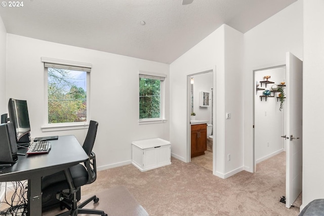 office space featuring light colored carpet, vaulted ceiling, and plenty of natural light