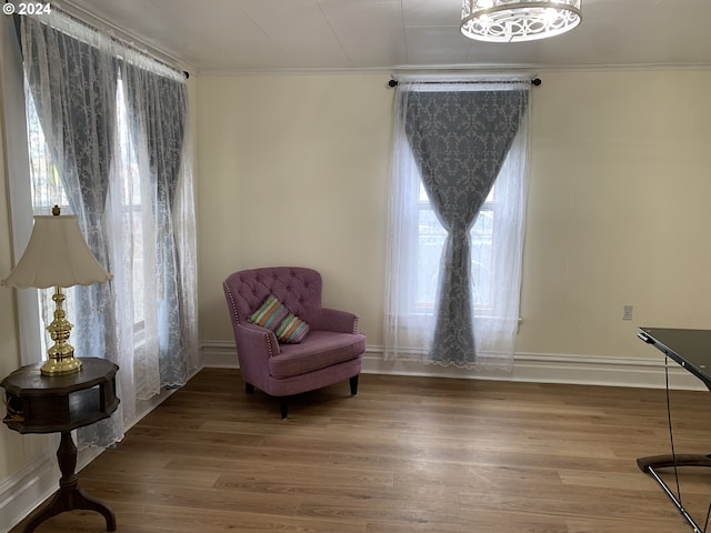 sitting room with ornamental molding, a healthy amount of sunlight, hardwood / wood-style floors, and an inviting chandelier