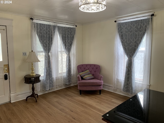 sitting room with crown molding, a notable chandelier, and wood-type flooring