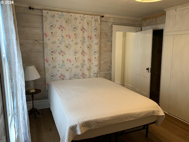 bedroom featuring dark wood-type flooring and wooden walls