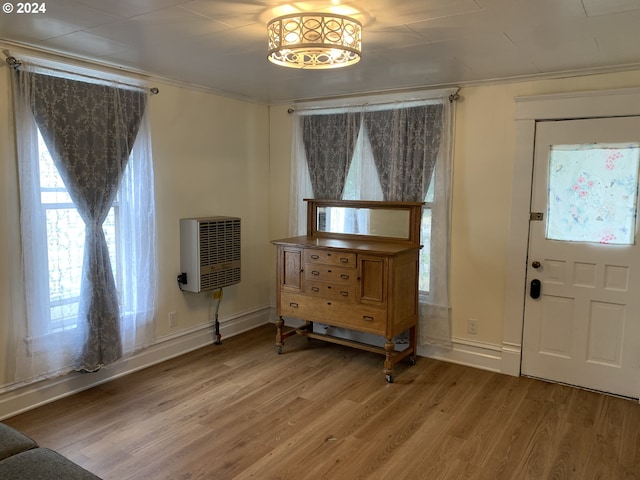 entrance foyer with ornamental molding, wood-type flooring, and heating unit