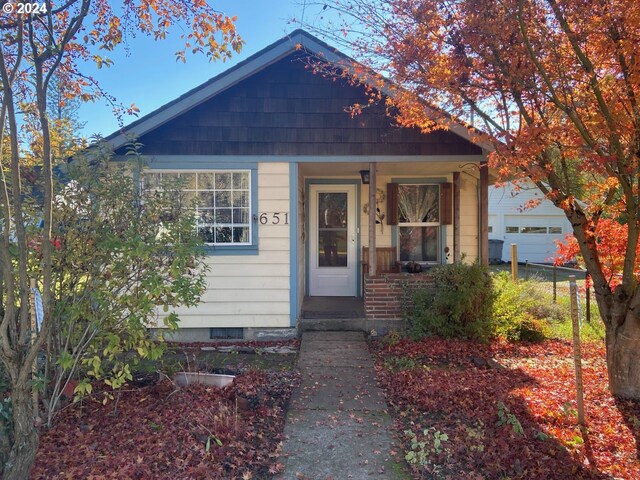 bungalow featuring covered porch, a garage, and an outbuilding