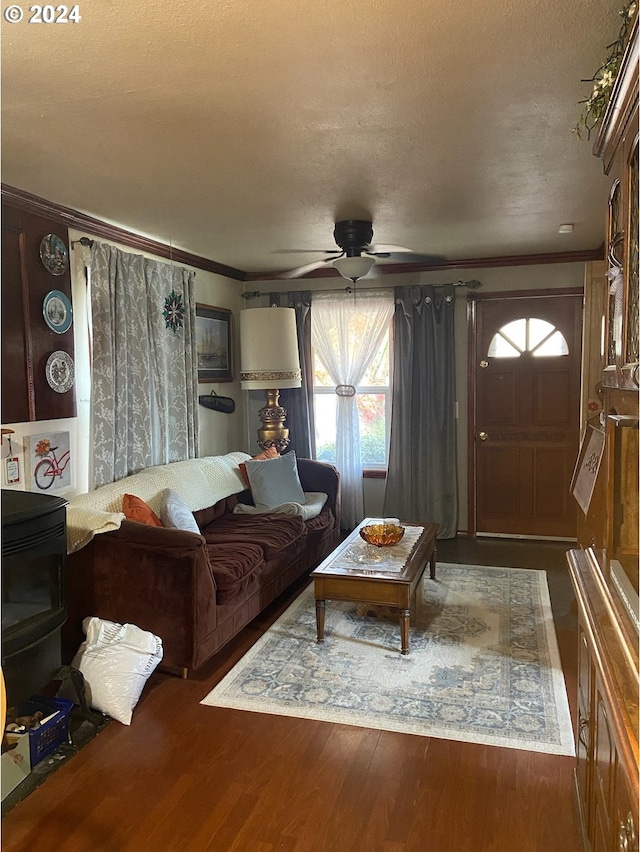 living room with a textured ceiling, dark hardwood / wood-style flooring, ceiling fan, and crown molding