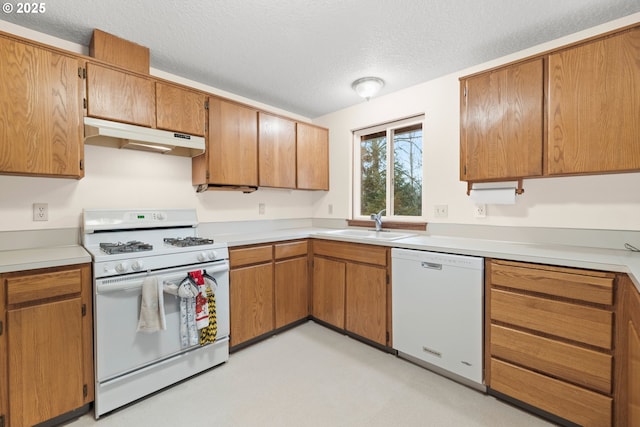 kitchen featuring a textured ceiling, light countertops, under cabinet range hood, white appliances, and brown cabinetry