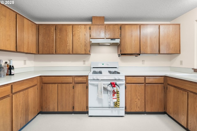 kitchen featuring white range with gas cooktop, a textured ceiling, brown cabinets, and under cabinet range hood