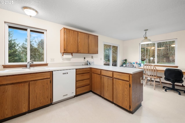 kitchen featuring a peninsula, a sink, light countertops, dishwasher, and pendant lighting