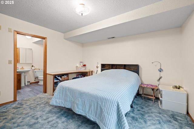 bedroom featuring carpet, ensuite bathroom, baseboards, visible vents, and a textured ceiling