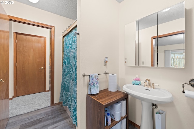 bathroom with a shower with curtain, a textured ceiling, and wood finished floors