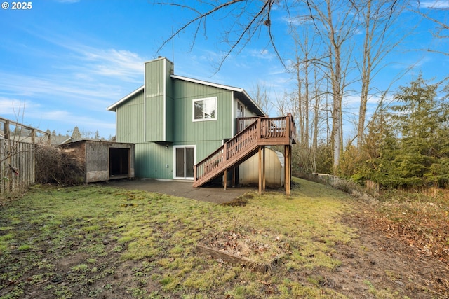 rear view of house featuring a deck, fence, a lawn, and stairs
