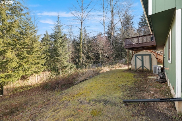 view of yard featuring a fenced backyard, an outdoor structure, a deck, and a storage shed