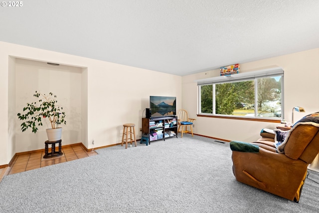 carpeted living room featuring a textured ceiling, visible vents, tile patterned flooring, and baseboards