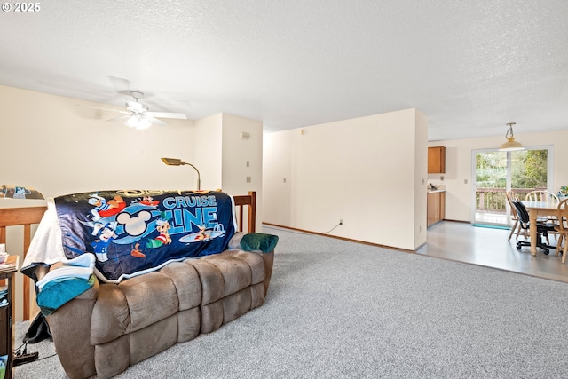 living room with a ceiling fan, light colored carpet, a textured ceiling, and baseboards