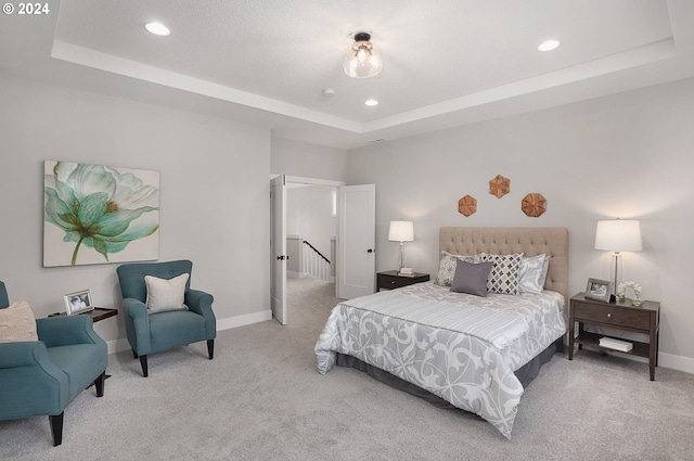 bedroom featuring a raised ceiling and light colored carpet