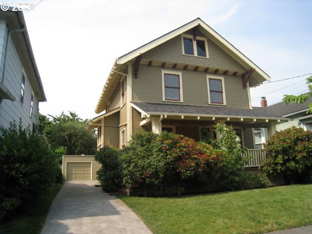 victorian house featuring a garage, covered porch, and a front yard