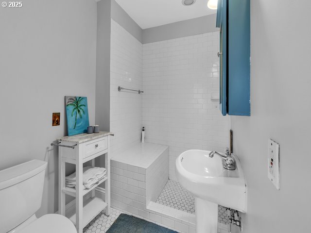 full bathroom with toilet, a sink, and tile patterned floors