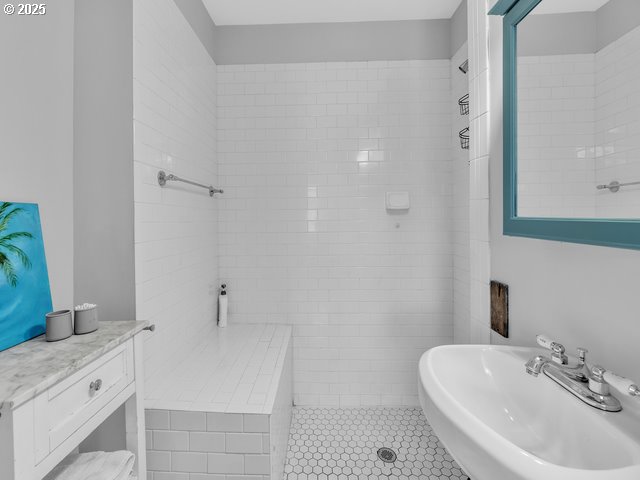 bathroom featuring tile patterned flooring, a walk in shower, and a sink