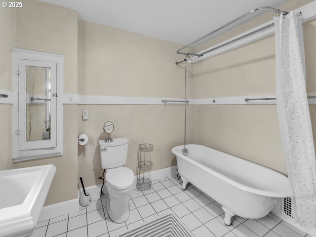 full bath with tile patterned flooring, baseboards, shower / bathtub combination with curtain, and toilet