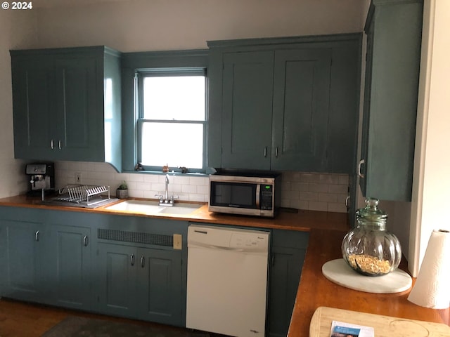 kitchen featuring a sink, tasteful backsplash, stainless steel microwave, and dishwasher