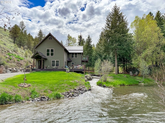 rear view of property with a lawn and a deck with water view