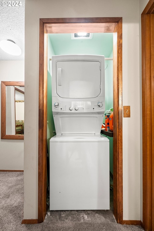 clothes washing area featuring stacked washer and dryer, carpet, and a textured ceiling