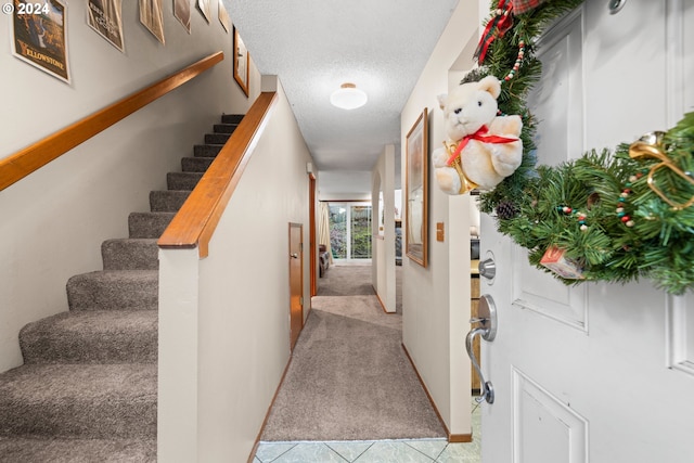 hallway featuring a textured ceiling and light colored carpet