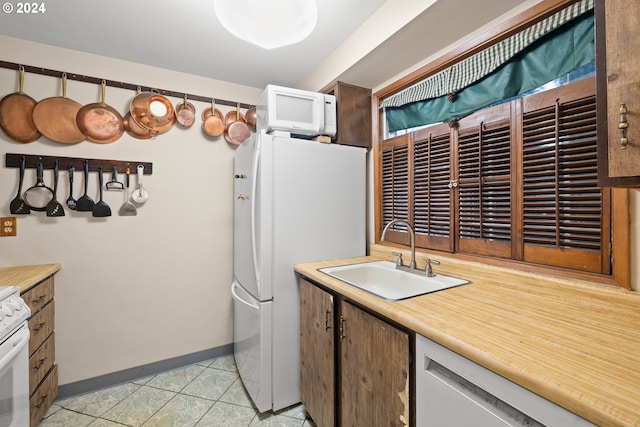 kitchen with light tile patterned floors, white appliances, and sink