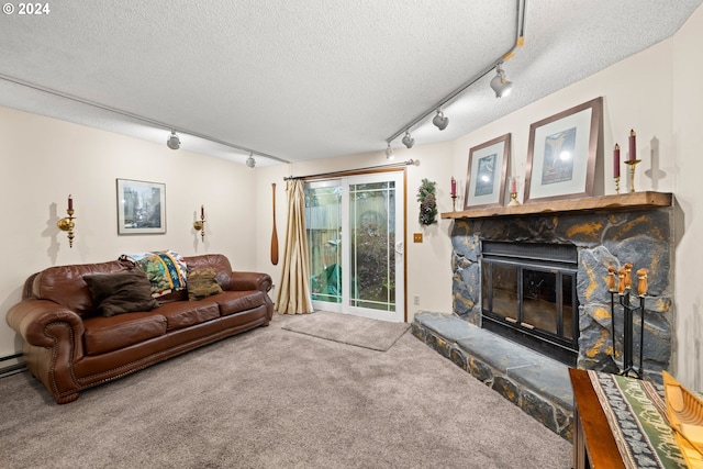 living room with carpet, a stone fireplace, a textured ceiling, and track lighting