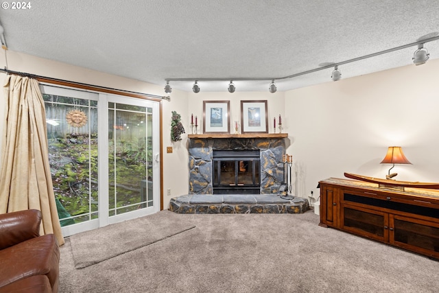 carpeted living room with a textured ceiling, rail lighting, and a stone fireplace