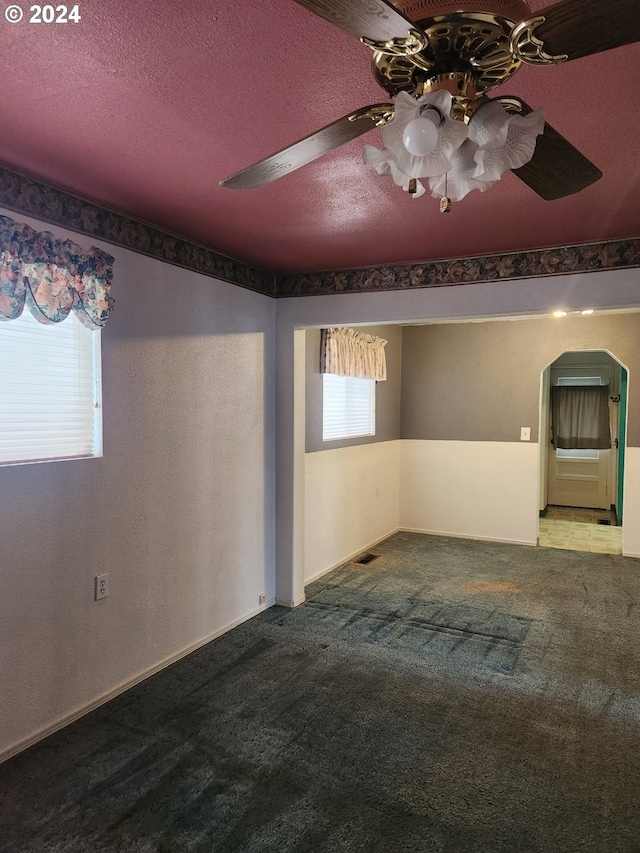 carpeted spare room featuring a textured ceiling and ceiling fan