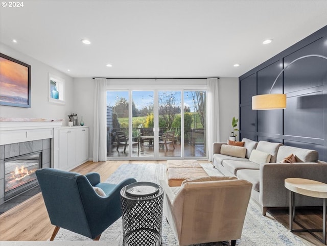 living room with a tile fireplace and light hardwood / wood-style floors