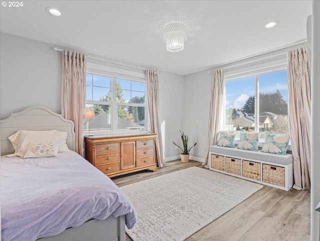 bedroom with multiple windows, light hardwood / wood-style flooring, and a chandelier