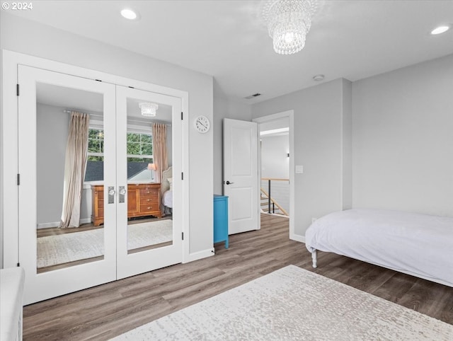 bedroom with hardwood / wood-style floors, french doors, and an inviting chandelier