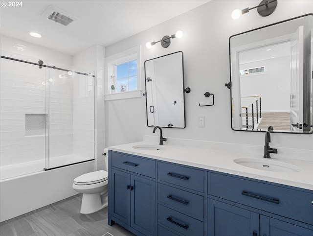 full bathroom featuring vanity, toilet, and bath / shower combo with glass door