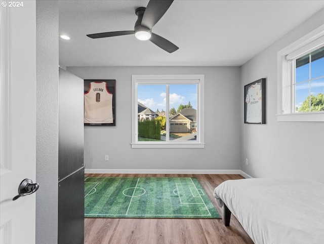 bedroom with multiple windows, wood-type flooring, and ceiling fan