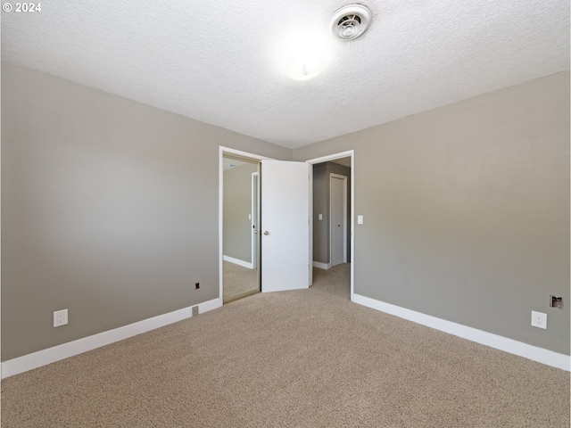 empty room featuring a textured ceiling and carpet