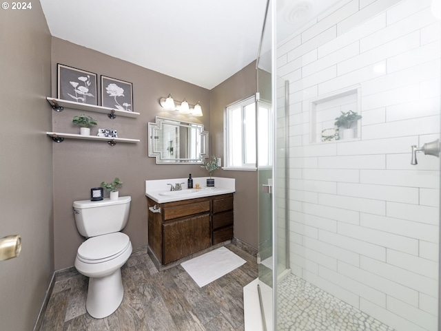 bathroom with hardwood / wood-style floors, a shower with shower door, vanity, and toilet