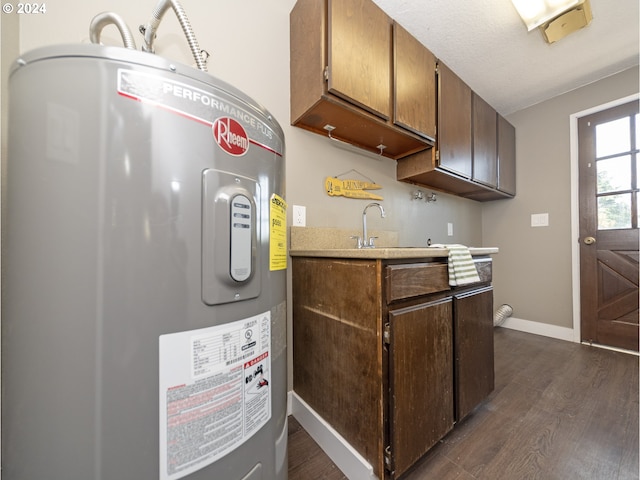 kitchen featuring electric water heater, sink, dark wood-type flooring, and a textured ceiling