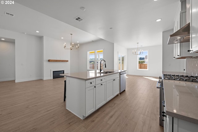 kitchen with sink, decorative light fixtures, stainless steel appliances, and an island with sink