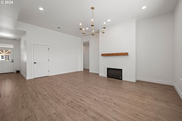 unfurnished living room featuring a chandelier and light wood-type flooring