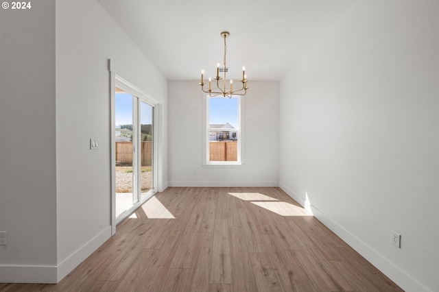 unfurnished dining area with a chandelier and light hardwood / wood-style flooring