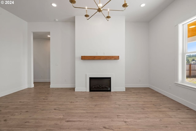 unfurnished living room with a notable chandelier and light wood-type flooring