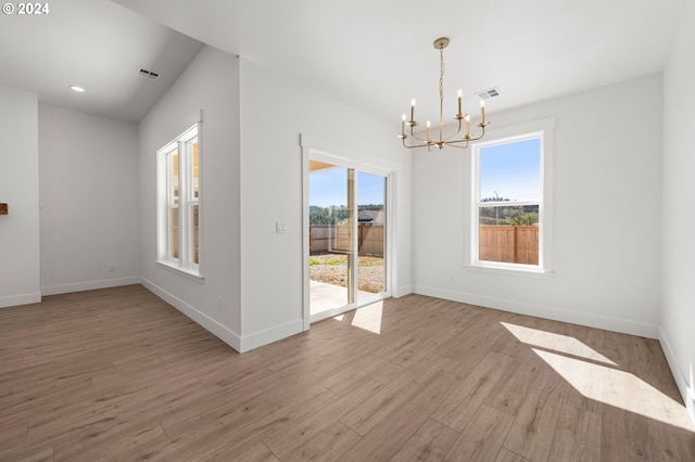 unfurnished room featuring light wood-type flooring and a notable chandelier