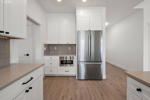 kitchen with white cabinetry, decorative backsplash, light hardwood / wood-style floors, and appliances with stainless steel finishes