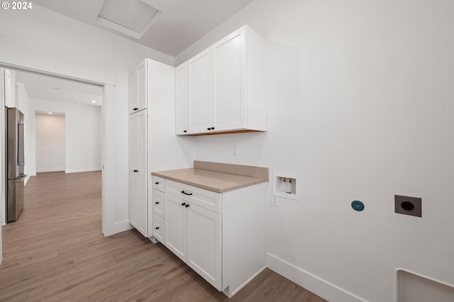 clothes washing area with cabinets, light wood-type flooring, electric dryer hookup, and washer hookup