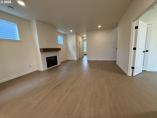 unfurnished living room featuring a tile fireplace and light wood-type flooring